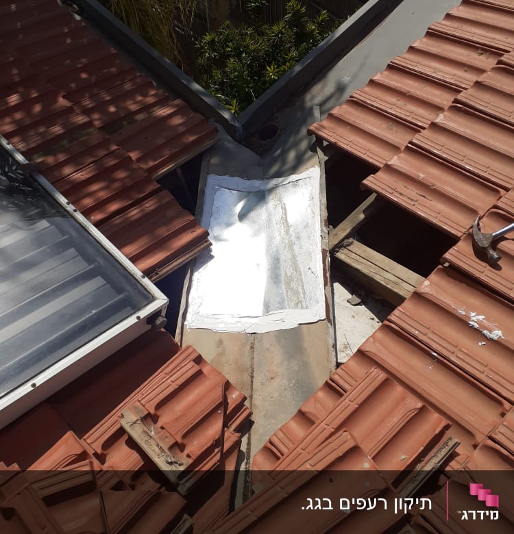 רעפים אדומים על גג עם תיקון לבן במרכז